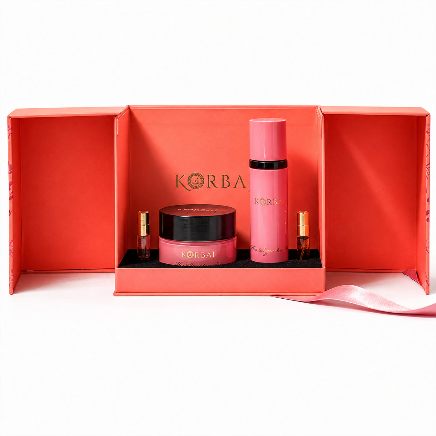 Front view of Korbaj Her Signature body gift set: pink body spray, dusting powder jar and two perfume minis in an open coral box.