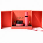 Front view of Korbaj Her Signature body gift set: pink body spray, dusting powder jar and two perfume minis in an open coral box.