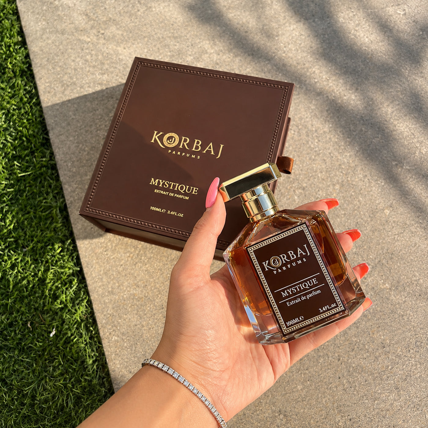 Korbaj Mystique 100ml woody aromatic perfume for men: hand-held bottle beside a diagonally placed brown box.