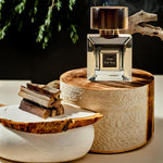 Korbaj Oud For You 100ml unisex Arabian oud perfume: bottle on a wood pedestal with wood pieces and vanilla flowers.