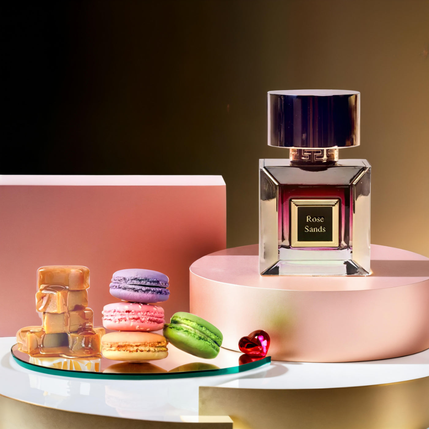 Korbaj Rose Sands 100ml vanilla gourmand perfume for women: bottle and pink box on a pink pedestal with macarons and caramel.