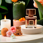 Korbaj Scarlet Amber 100ml unisex floral amber perfume: bottle on a cream pedestal with a candle, flowers, caramel and citrus.